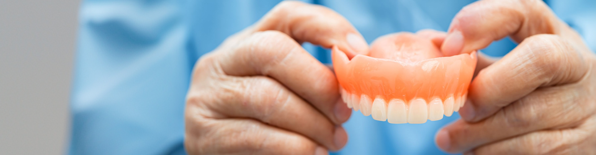 Hands holding upper denture.